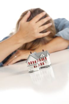 Woman with Head in Hand Behind Model Home on a White Surface.