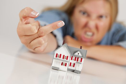 Angry Woman Flipping The Bird Behind Model Home on White Surface.