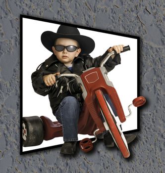 Two year old baby boy playing like a biker on his tricycle