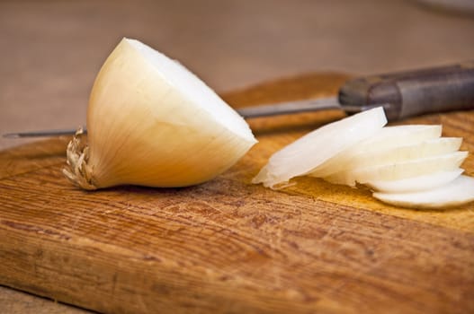 Cutting an onion to use in a meal. Food preparation on a cutting board with a knife.