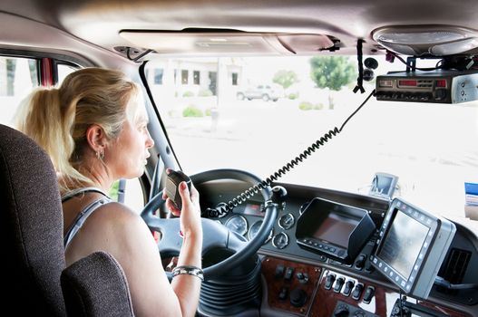 Woman truck driver in a big rig talking on the C.B. radio.