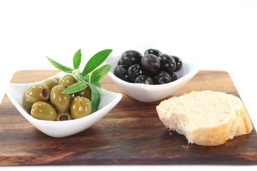 black and green olives with olive branch on a wooden board