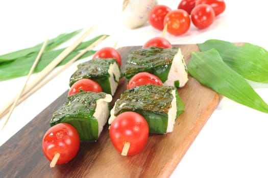 Feta cheese in wild garlic coat with cherry tomatoes on a skewer