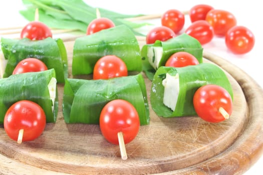 Feta cheese in wild garlic coat with cherry tomatoes on a skewer
