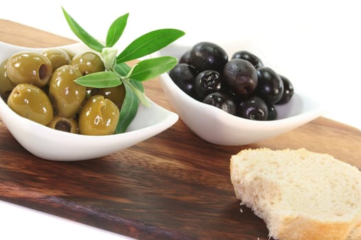 black and green olives with olive branch on a wooden board