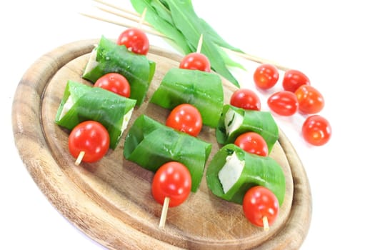 Feta cheese in wild garlic coat with cherry tomatoes on a skewer