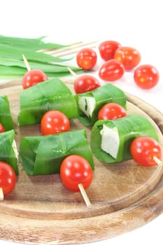 Feta cheese in wild garlic coat with cherry tomatoes on a skewer
