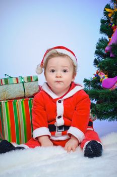 Christmas theme: little Santa - Surprised baby boy with gifts. Vertical view