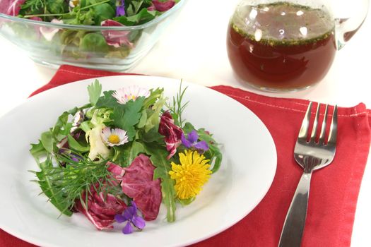 Wild herb salad with balsamic oil dressing on a white background