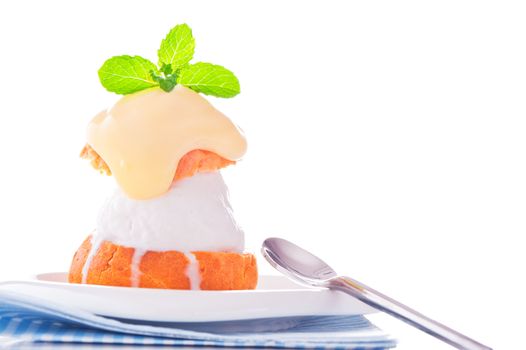 Profiterole in a small plate with ice cream vanilla sauce and mint leaf on a white backgound