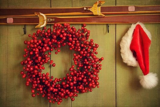 Christmas wreath with Santa hat hanging on rustic wall