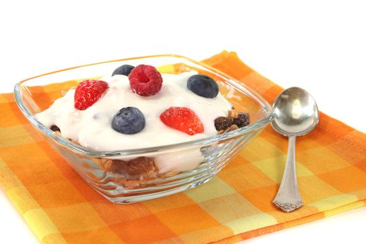 Cereal bowl with yogurt, fresh fruit, nuts and milk in front of white background