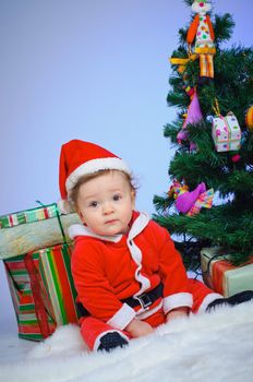 Christmas theme: little Santa - Surprised baby boy with gifts. Vertical view