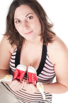 Portrait of pretty pregnant woman with baby shoes isolated on white