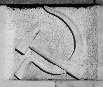 Communist hammer and sickle symbol on stone. Black and white picture