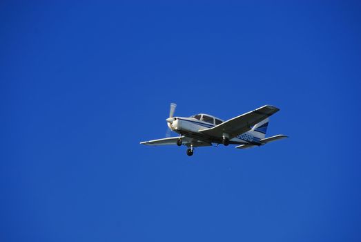 A trainer glider plane isolated against a clear blue sky