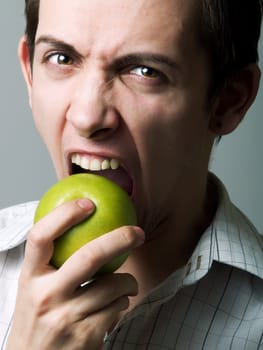 Young man eating a green apple