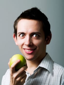 Young man eating a green apple