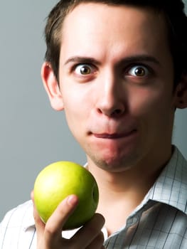 Young man eating a green apple