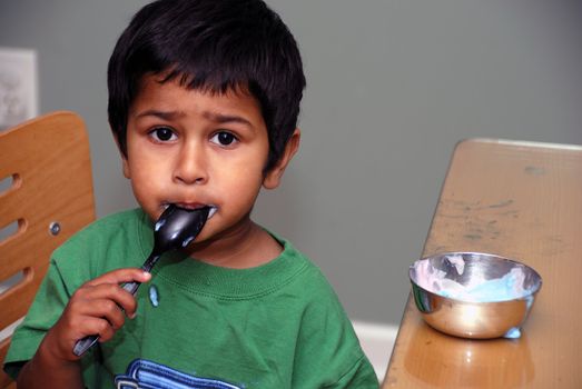 An handsome indian kid enjoying his yoghurt