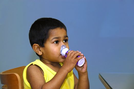 An handsome indian kid enjoying his yoghurt