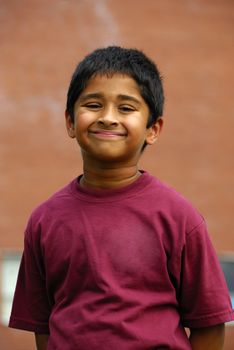 A happy Indian school kid smiling in front of the classroom