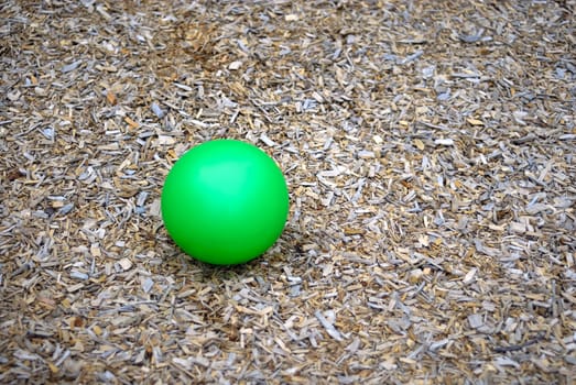 A green ball isolated on a wooden chip back ground