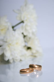 wedding rings and white chrysanthemumon on a grey background. Shallow DOF