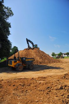 Two heavy machines moving and reshaping the spoil heap.