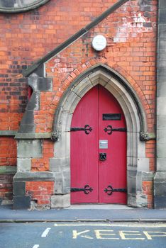 Old red, wooden doors built in gothic arch.