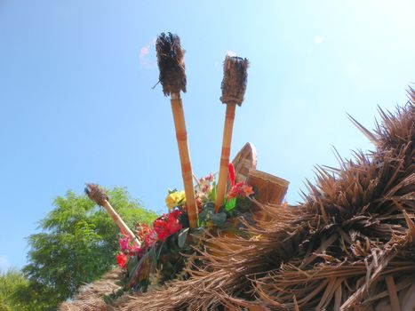 tiki torches no the top of a hut, ringed by flowers.