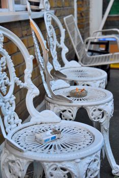 Empty chairs in the garden look like they have been waiting with someone for someone else. Now only cigarets remind about anyones presence.