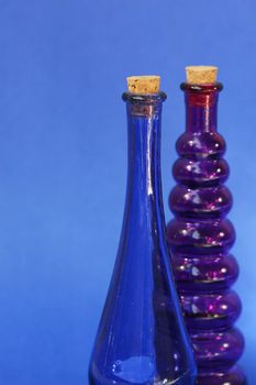 Empty blue and purple glass bottle with corks in the tops. Shot against a blue background