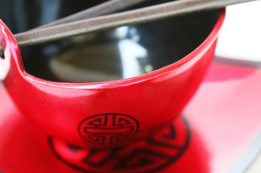 An oriental bowl with chopsticks on a matching plate