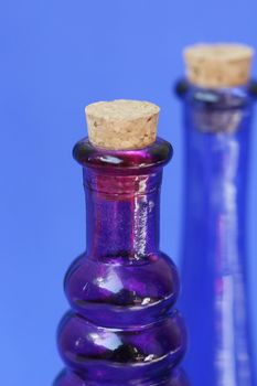 Empty blue and purple glass bottle with corks in the tops. Shot against a blue background