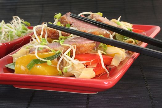 Duck breast with fried noodles, fresh vegetables and radish sprouts
