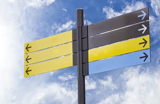 Colorful plastic informational signs with arrows. Show the direction. Against the blue sky with clouds