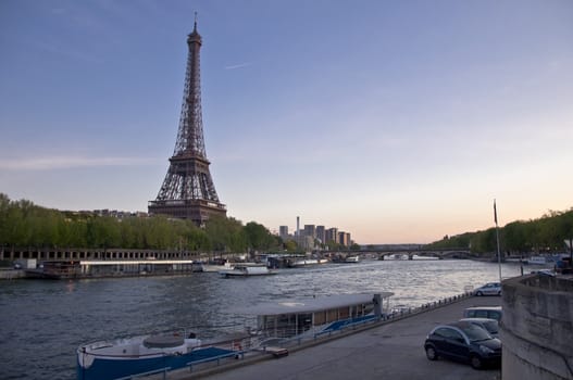 Eiffel Tower on the banks of the River Seine at sunset. Urban night landscape.