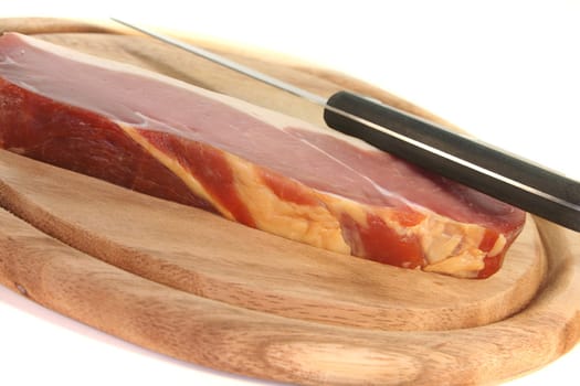 smoked bacon with a knife on a wooden board
