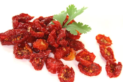 fresh dried tomatoes with a cilantro leaf on white background