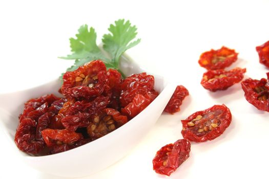 fresh dried tomatoes with a cilantro leaf on white background