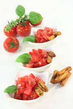 some bread sticks, tomatoes and basil on a light background