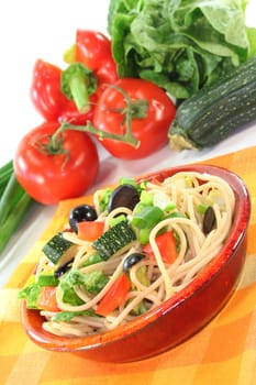 a bowl of pasta salad with spaghetti and fresh vegetables