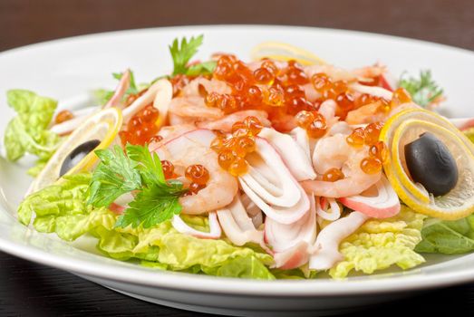 Salad with shrimps, caviar, calamaries, lettuce, lemon and olive