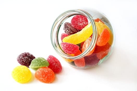 a glass of colorful fruit jelly on white background