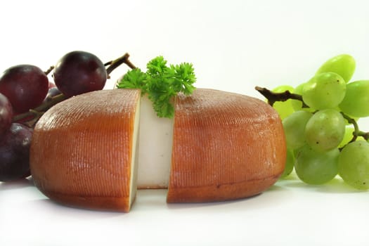 a loaf of cheese with fresh grapes on a white background