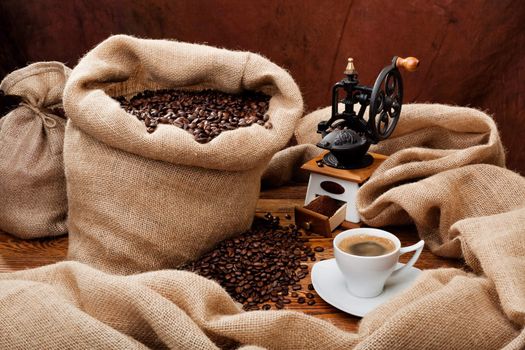 Studio photo of sack with scattered coffee grain, and cup of espresso