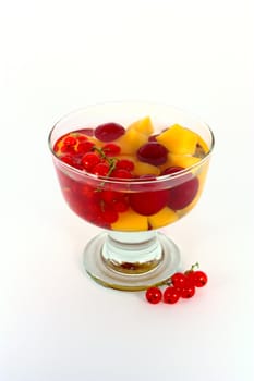 Peach compote with fresh red currants in glass bowl isolated on white