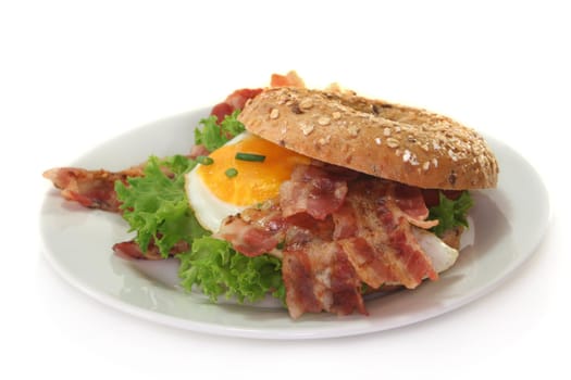 Bagel with salad, fried egg and crispy bacon
