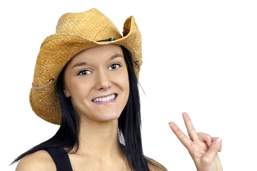 Pretty young cowgirl wearing a straw cowboy hat smiling and making the peace sign with her fingers.